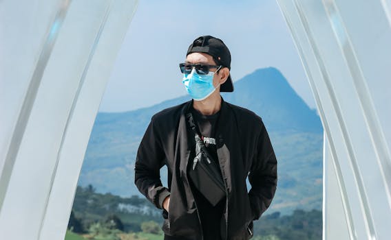 A man in sunglasses and a face mask enjoying the outdoors with a scenic mountain view.