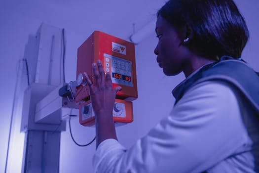 A professional woman in a lab coat operating an X-ray machine in a healthcare setting.