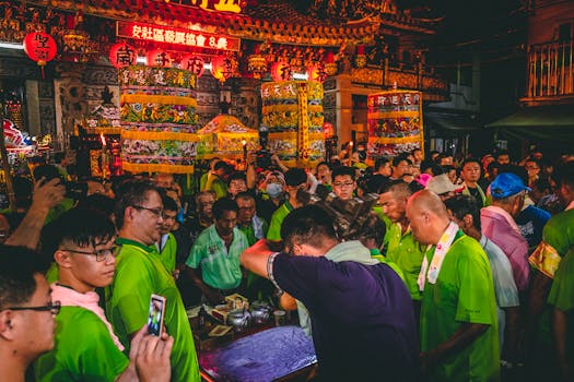 A vibrant night scene of people gathered at a Taiwanese temple for a traditional festival, celebrating under red lanterns.