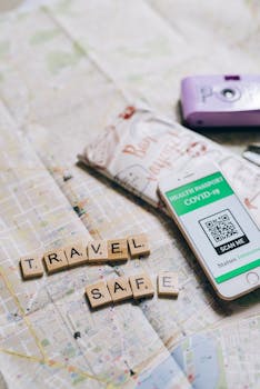 Flat lay of travel essentials including health passport and map, emphasizing safe travel.