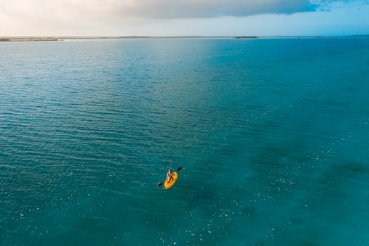 Kayaker paddling on tranquil turquoise ocean waters. Perfect scene for adventure and outdoor enthusiasts.