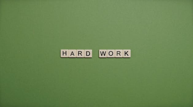 Tiles spelling 'hard work' on a green background symbolizing diligence and effort.